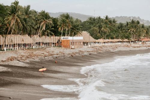 een persoon met een surfplank die op het strand staat bij Surfside El Tunco in Tamanique