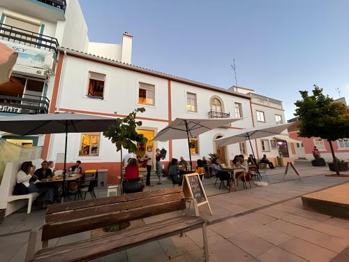a patio with people sitting at tables and umbrellas at Casa Das Batatas in Odeceixe