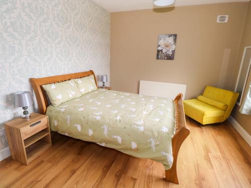 a bedroom with a bed and a yellow chair at Carrowreagh in Aclare