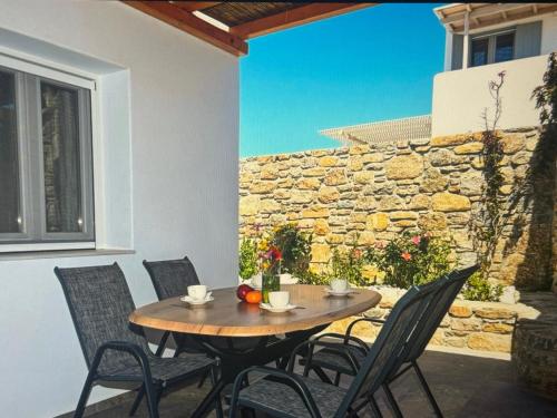 een tafel en stoelen op een patio met een stenen muur bij Super views in Mykonos in Panormos Mykonos