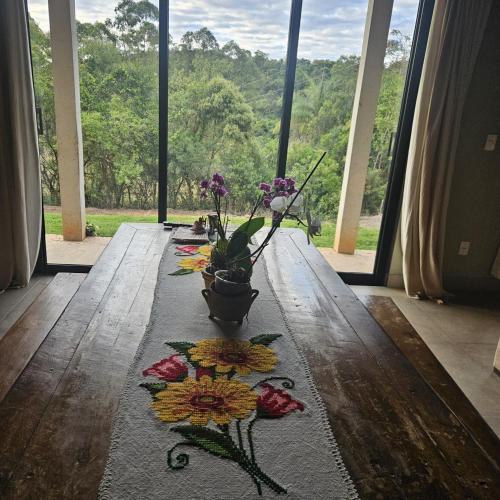 a table with flowers on it in front of a window at Sitio Encanto in João Ribeiro