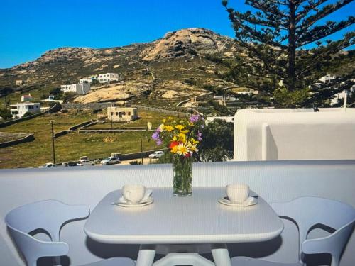 een tafel met twee kopjes en een vaas met bloemen bij Super views in Mykonos in Panormos Mykonos
