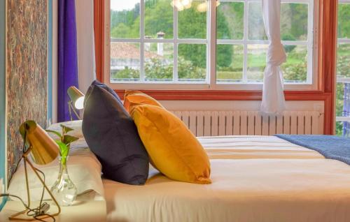 a bedroom with a bed with pillows and a window at Villa Rosa Luxury Singular in Padrón