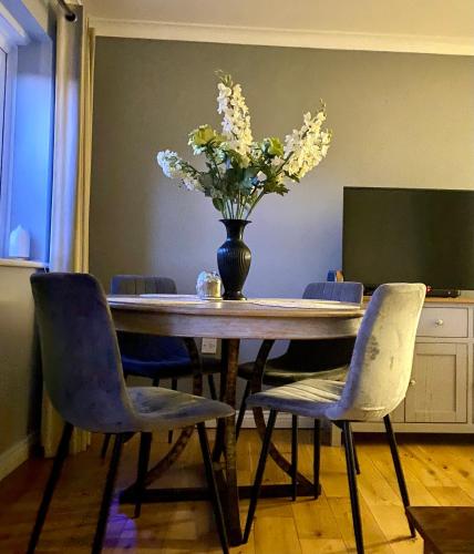 a dining room table with a vase of flowers on it at Modern house easy access Norwich city and broads in Spixworth