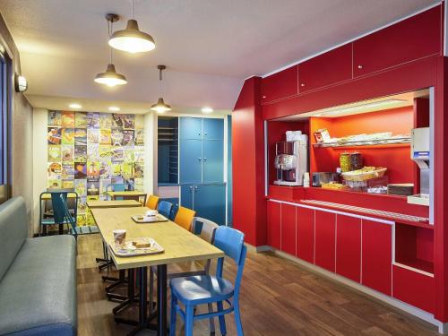 uma sala de jantar com paredes vermelhas e uma mesa e cadeiras em hotelF1 Rouen Zénith Parc Expo em Saint-Étienne-du-Rouvray