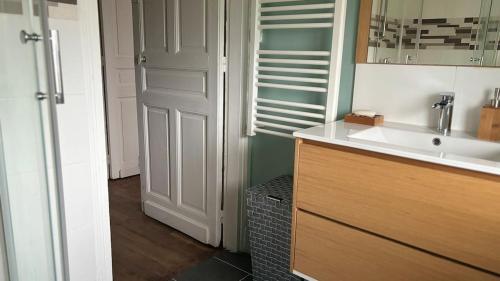 a bathroom with a sink and a mirror and a door at T2 proche du CH d'Arras in Sainte-Catherine