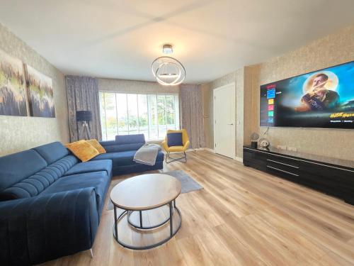 a living room with a blue couch and a flat screen tv at Entire Spacious 3-Bed Family Home, City Centre, Free Parking, Garden in Glasgow