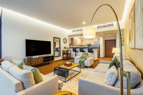 a living room with white furniture and a flat screen tv at Champions' Apartment - Balcony Sunsets - Rooftop Pools - Modern Oasis - Family Heaven - Full Canal Views - 2 min walk from Space42 Arena in Abu Dhabi