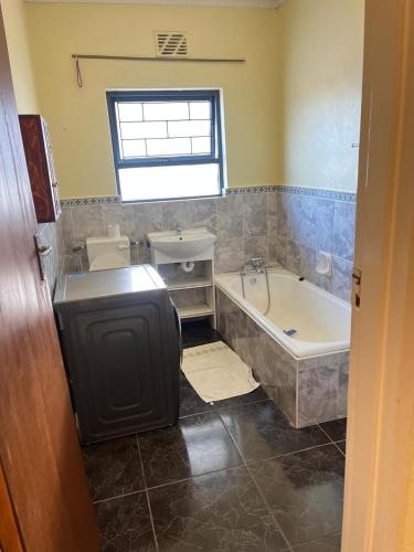 a bathroom with a tub and a toilet and a sink at Black chilli accommodation in Brackenfell