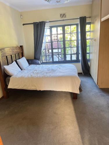 a bedroom with a large bed and a large window at Black chilli accommodation in Brackenfell