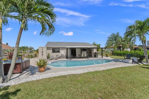 a house with a swimming pool and palm trees at Lush - Tropical - Modern Home - Heated Pool and Spa in Port Saint Lucie