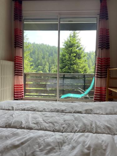 a bedroom with a large window with a bed and a swing at chalet vassivière in Le Lioran