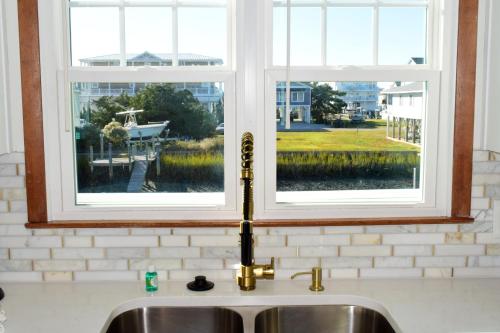 a kitchen sink with two windows above it at Keepin It Reel in Holden Beach