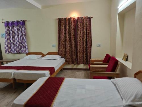a room with three beds and a window with curtains at Daya Dharmam Residency in Tiruvannāmalai