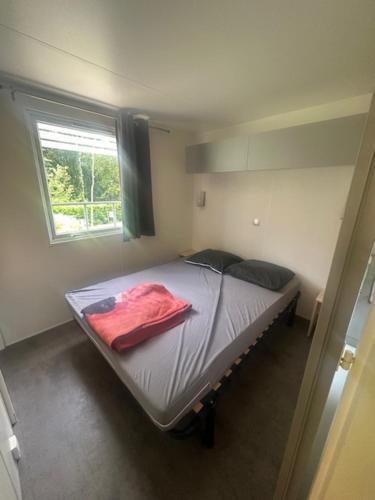 Un dormitorio con una cama con una manta roja encima. en Camping Le Ruisseau, en Saint-André-de-Seignanx