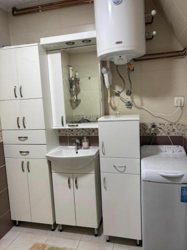 a bathroom with white cabinets and a sink and a mirror at ZlatniBor House Zlatibor in Vodice