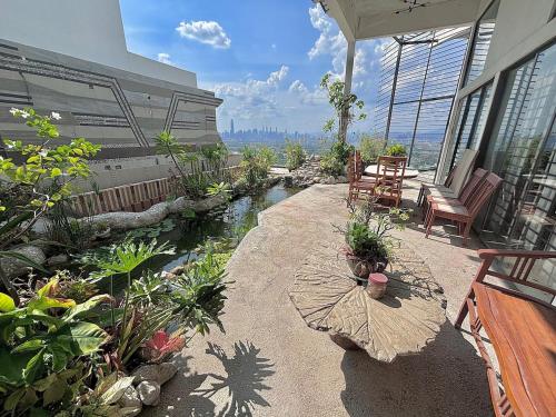 eine Terrasse mit Teich und Stühlen an einem Gebäude in der Unterkunft KL Ampang Flora Eco Luxury Hilltop Villa in Ampang