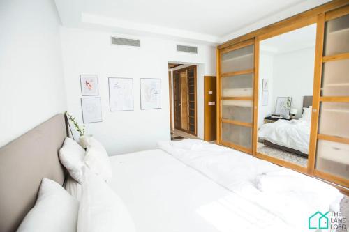 a white bedroom with a bed and a mirror at Le Premium Central luxueux et très confortable in Dār Şāliḩ Bey