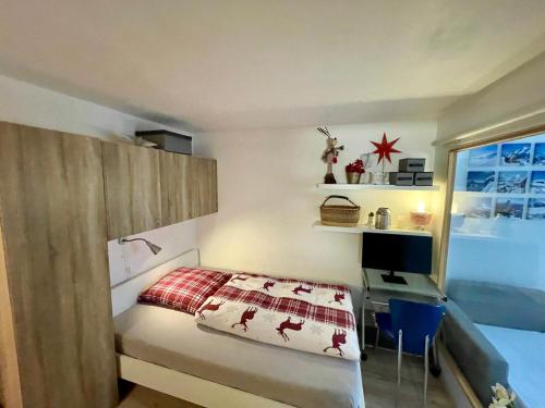 a bedroom with a bed and a desk and a window at Ferienwohnung Gemmiblick in Leukerbad