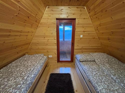 two beds in a wooden room with a window at ZlatniBor House Zlatibor in Vodice