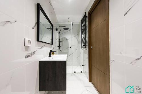 a bathroom with a sink and a mirror and a shower at Sunset 204 Luxury 2 bedrooms with Gym in Carthage