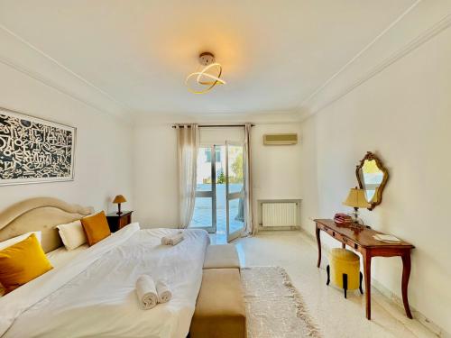 a bedroom with a bed and a table and a mirror at Safran II Appartement très central avec Terrasse à la Marsa in Dar el Ouzir