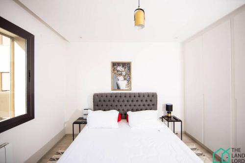 a white bedroom with a bed and two tables at B13 New cosy 1 bedroom in La Marsa in Sidi Daoud