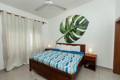 a bedroom with a bed with a large leaf on the wall at Smile Homes in Zanzibar City