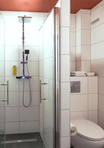 a bathroom with a shower with a toilet and a glass shower door at Boutique Hotel Zum grünen Baum in Alzenau