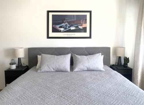 een slaapkamer met een bed met twee nachtkastjes en een ingelijste foto bij Apartment ANi, E-Parkplatz Göppingen 2Zi, 60qm zentrale Wohnung, Zweifamilienhaus, Terrasse, Garten, ruhig, direkt an Fahrradstraße, nahe EWS Arena in Göppingen