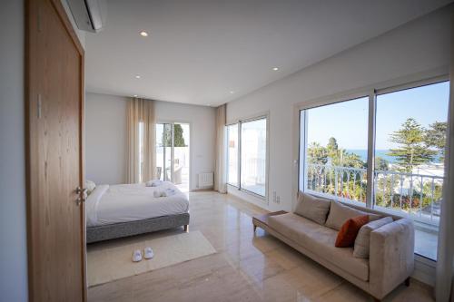 El HaouachにあるVilla Hermes: Seaside and luxuriousのベッドとソファと窓のある寝室