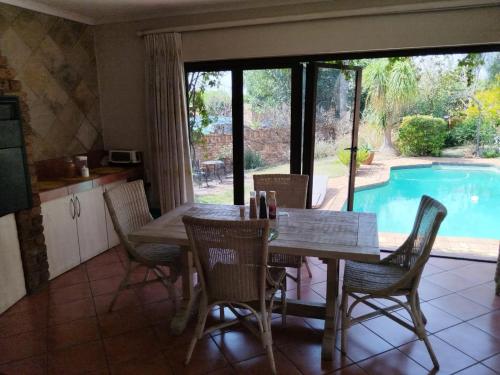 a dining room with a table and chairs and a pool at Feather Tree Bed and Breakfast in Centurion