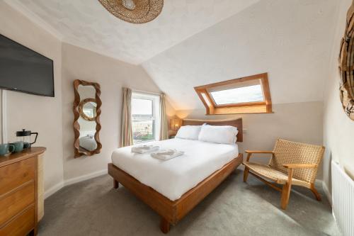a bedroom with a bed and a tv and a chair at Rwts Rooms & Resto in Broad Haven