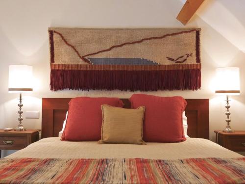 a bedroom with a large bed with two red pillows at Quinta do Tedo in Folgosa