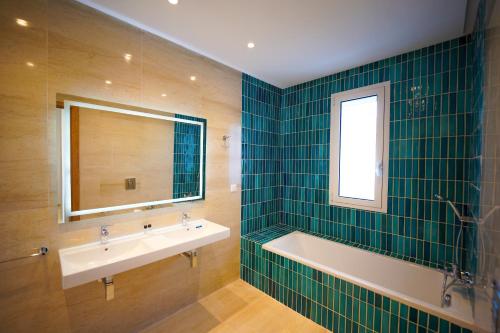 a bathroom with a tub and a sink and a mirror at Villa Apollon: Seaside and luxurious in El Haouach