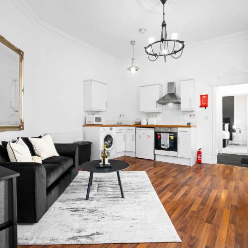 a living room with a black couch and a table at Stylish Apartment - Wolverhampton - Fast Wi-Fi - Parking 9PC in Wolverhampton