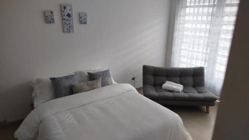a bedroom with a white bed and a couch at Apartamento Limón Azul in Sogamoso