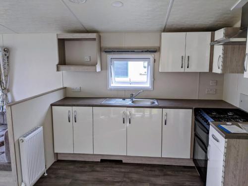 Una pequeña cocina con gabinetes blancos y un fregadero. en Seaview Holiday Rentals - Hailsham, en Chestfield