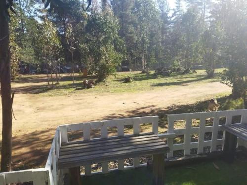 a white fence and a bench in a park at Cabañas Entre Bosques De Algarrobo in Algarrobo
