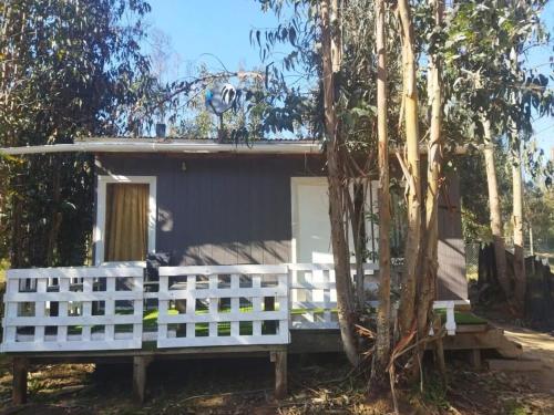 a small house with a white fence in front of it at Cabañas Entre Bosques De Algarrobo in Algarrobo
