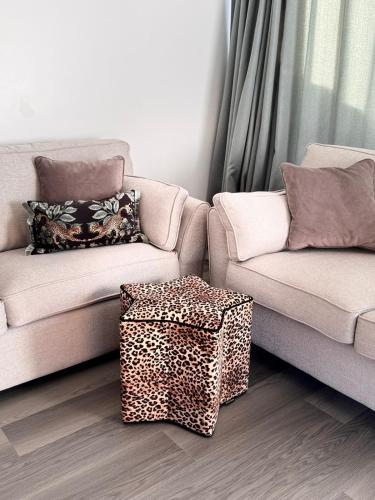 a living room with two couches and a leopard stool at The Rewind Retreat in Sandwich