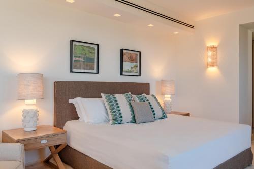 a bedroom with a bed with pillows and two lamps at La Tiara di Cervo in Liscia di Vacca