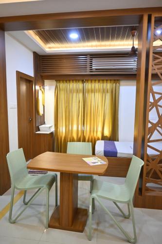 a dining room with a wooden table and chairs at Marudhan Grand in Kumbakonam