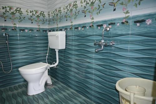 a bathroom with a toilet and a mural of water at Marudhan Grand in Kumbakonam