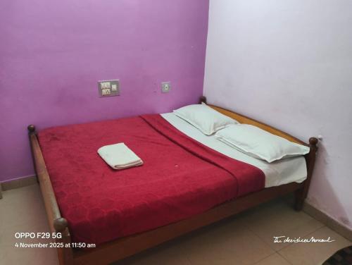 Una cama pequeña con una manta roja encima. en Srusti Residency Mysore, en Jāmb