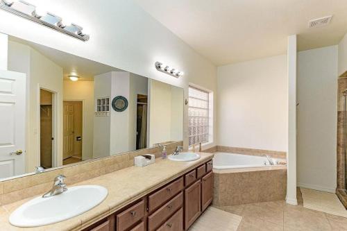 ein Badezimmer mit zwei Waschbecken, einer Badewanne und einem großen Spiegel in der Unterkunft Large house for entire family in Mesquite Creek