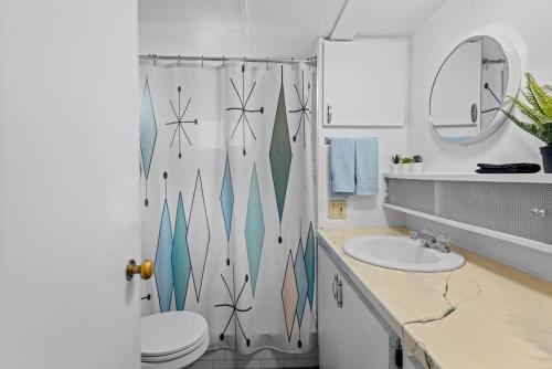 a bathroom with a shower curtain with a toilet and a sink at Beautiful Decorated Cozy Retreat in Rockaway Beach