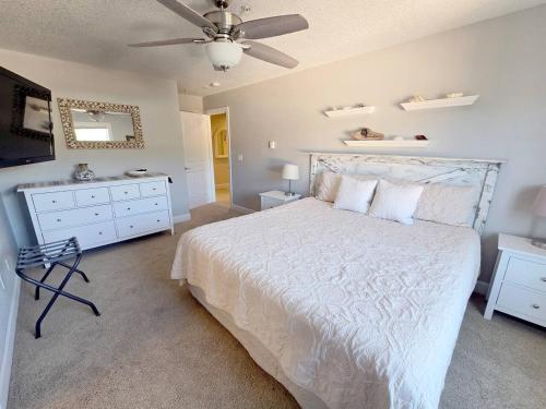 ein Schlafzimmer mit einem weißen Bett und einem Deckenventilator in der Unterkunft 2 Bedroom Condo in the Heart of Rockaway Beach in Rockaway Beach