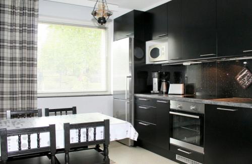 une cuisine avec des armoires noires et une table avec des chaises dans l'établissement Convenient Apartment for 3 in Varissuo, à Littoinen