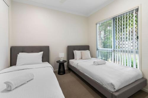two beds in a room with a window at Cozy 2BR Retreat in Peaceful Mount Warren Park in Windaroo